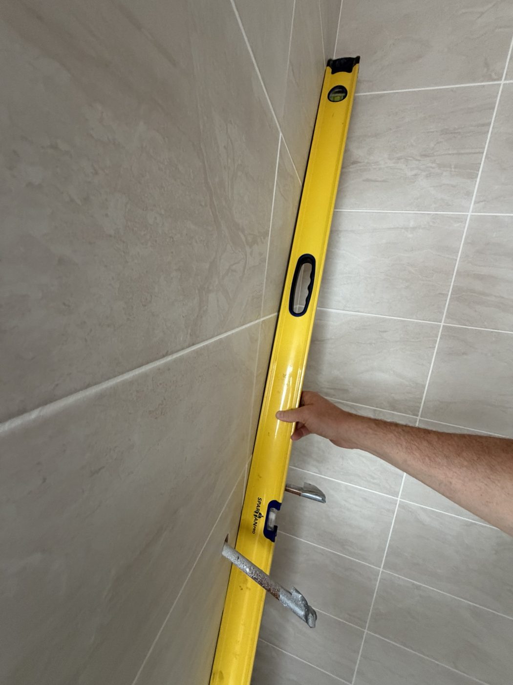 Spirit level used to check a tiled bathroom wall